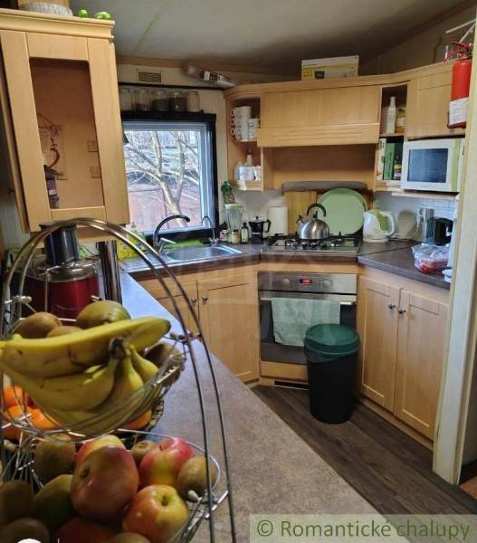 A kitchen with wooden cabinets, a stove, fruit on the table, ideal for a family home.