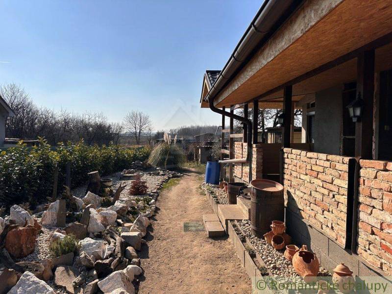Family house with a brick exterior, stone garden, clay pots, natural surroundings.