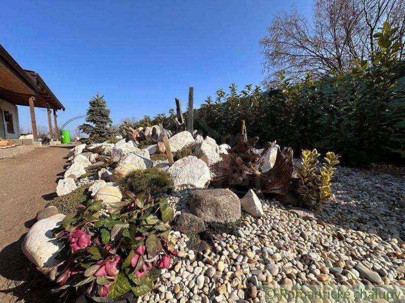 A family house surrounded by a garden with stone elements and colorful plants.