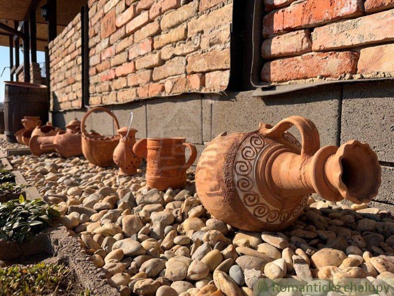 Ceramic jugs and containers decorate the exterior of the family house on a gravel garden.
