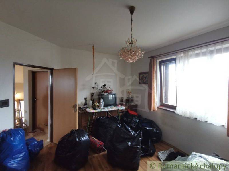 A living room in a family house with a chandelier, a television, and lots of bags on the floor.