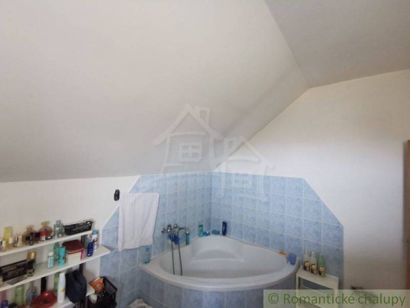 Attic bathroom with a bathtub and shelves in a family house. It exudes coziness and freshness.