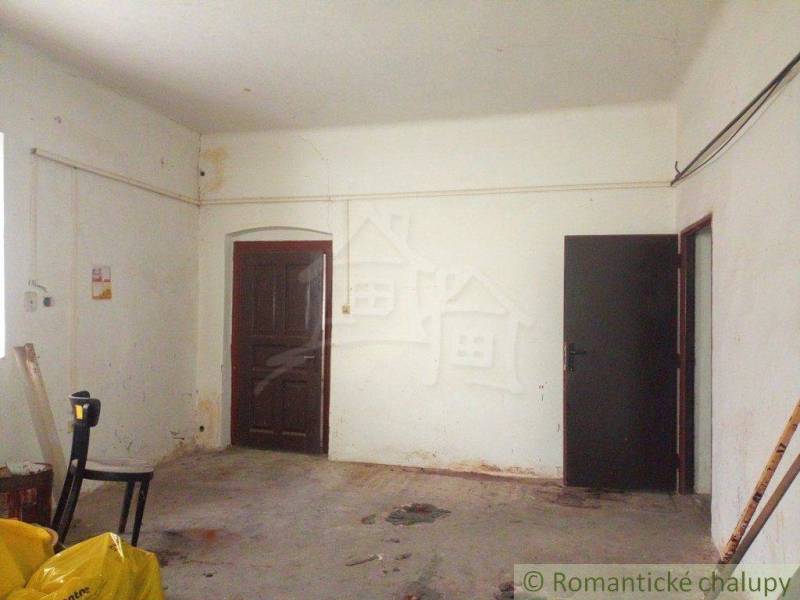 Spacious room with white walls in an older family house, open door.