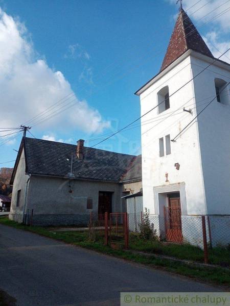A family house and a tower by the road in a village setting, green grass and blue sky.