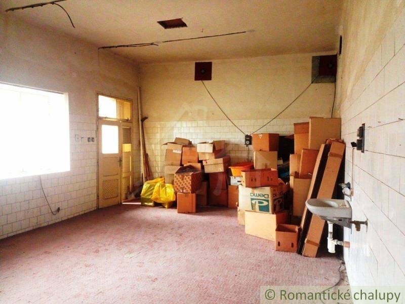 Interior of a family house with stored boxes and a sink, white tiles on the walls.