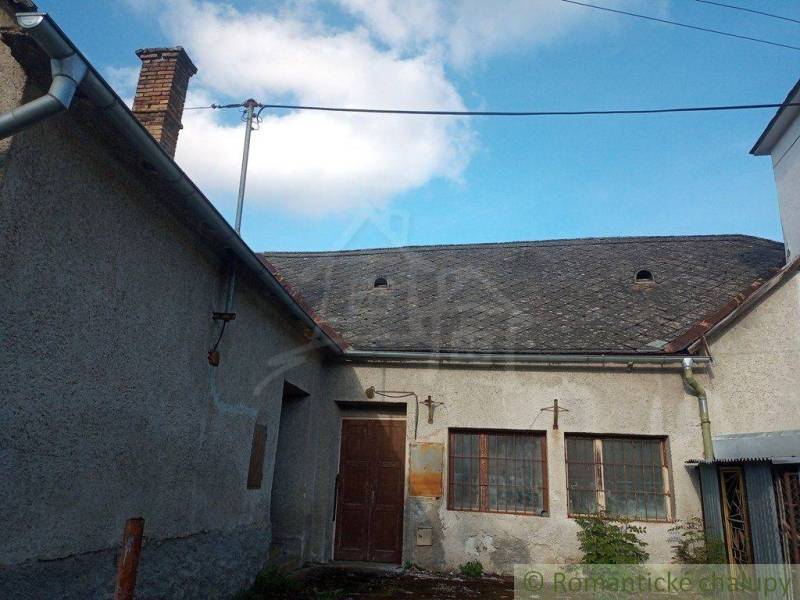 A family house with wooden windows, doors, and a shingle roof in the countryside.
