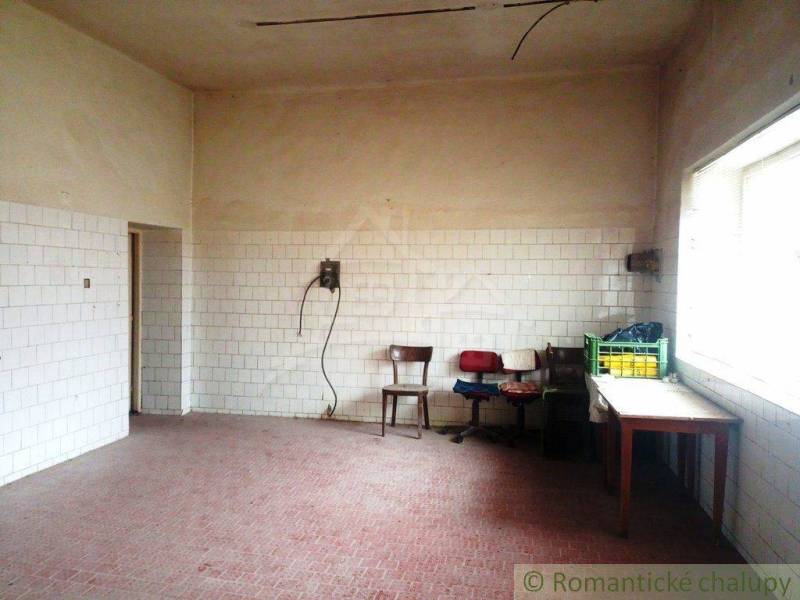 A spacious room with tiles on the walls, old chairs, heating, and natural lighting.