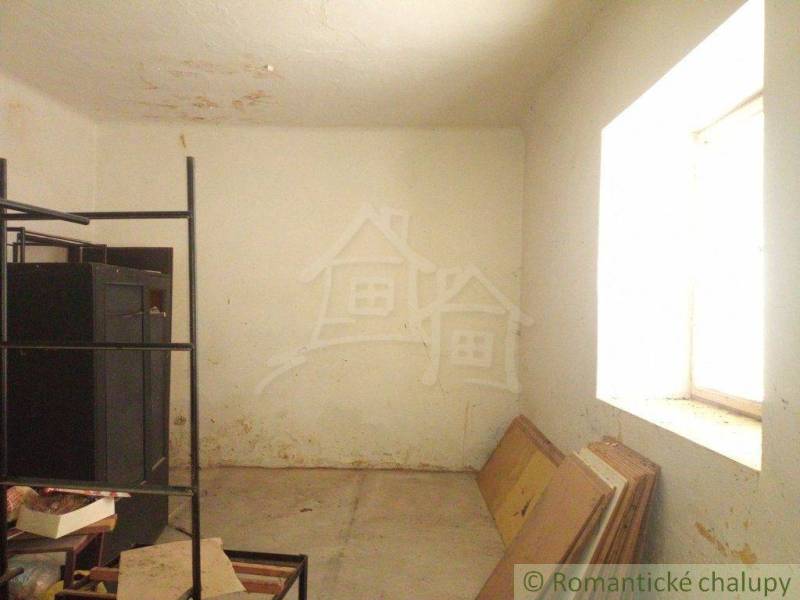 An empty room with a window, a shelf, and building materials in a family house.