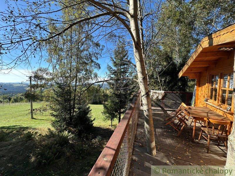 A wooden house with a terrace in the middle of the forest, offering a beautiful view of the landscape.