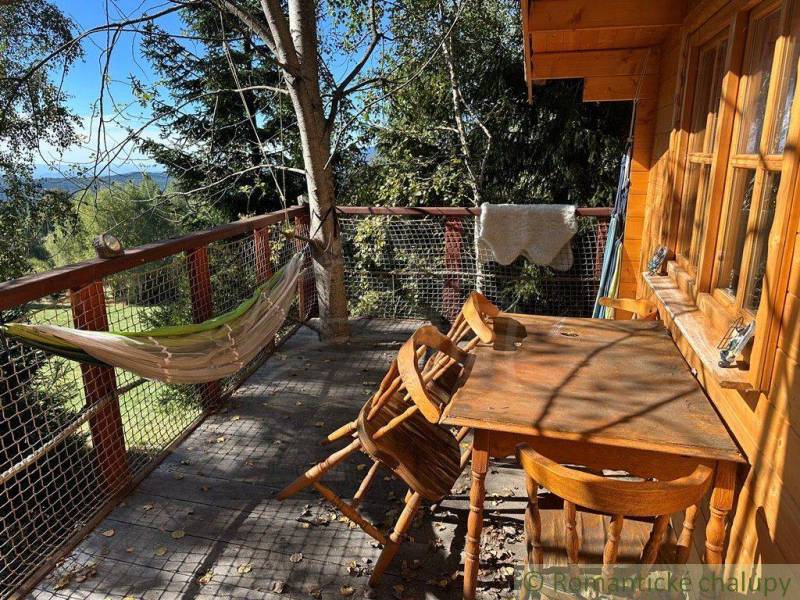 Wooden terrace, hammock, table, chairs, view of nature, family house.