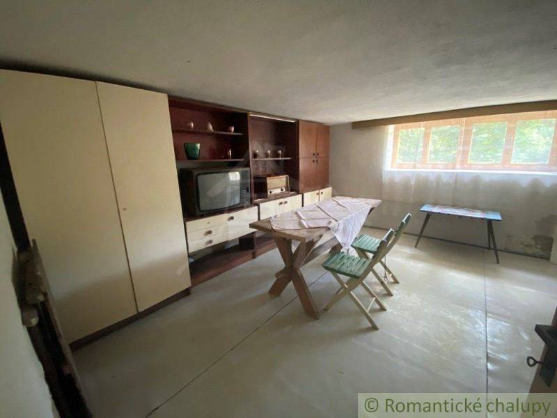 Retro living room with wooden furniture, television, and folding chairs in a family house.