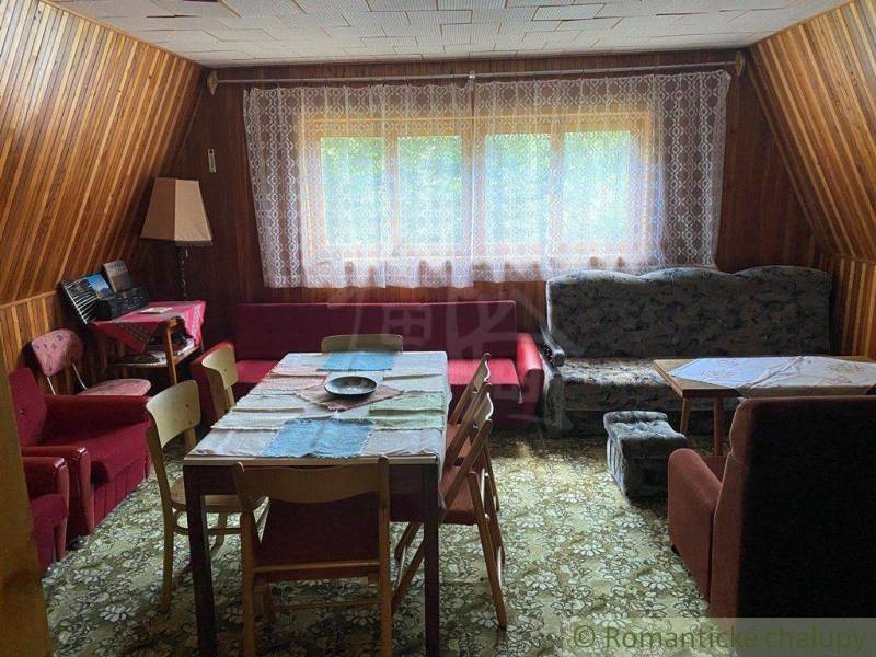 A living room with antique furniture, wooden walls, and a patterned carpet in a family house.