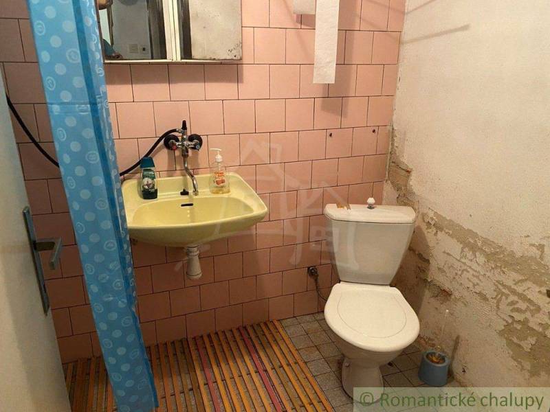 A bathroom with pink tiles, a sink, and a toilet, suitable for a family house.