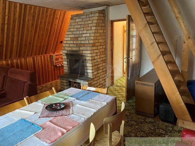 Dining nook with a sofa, tiled stove, and wood-paneled walls for a family house.