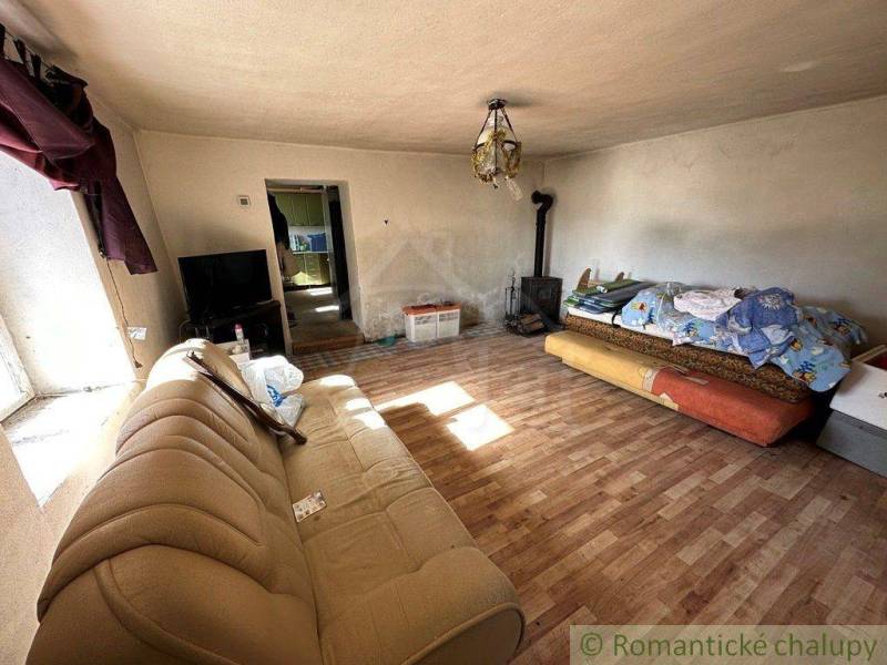 Living room in a family house with a sofa and a fireplace, next to a duvet on the bed.
