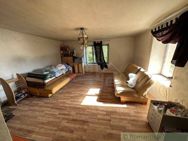 Living room in a family house, contains sofas, shelves, windows, and wooden flooring.