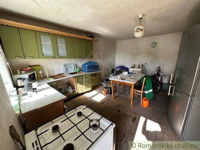 A kitchen with a gas stove, green cabinets, and a table in a family house.