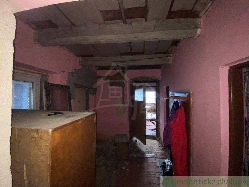 A room with old furniture in a family house with hanging clothes and unfinished walls.