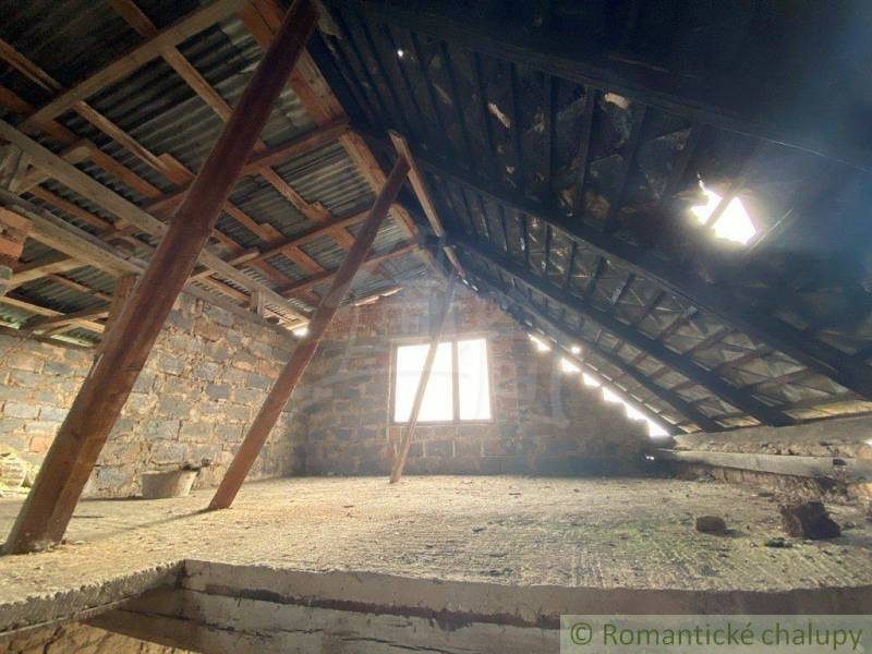 Attic with a sloped metal roof and brick walls in a family house.