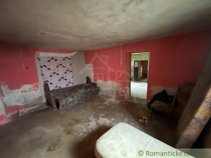 A room in a family house with a bed, damaged plaster, and a colorful wall.