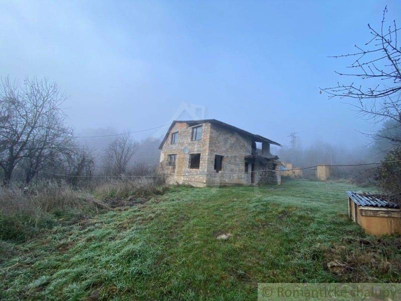 A stone family house in the countryside, surrounded by mist and trees, with a spacious plot.