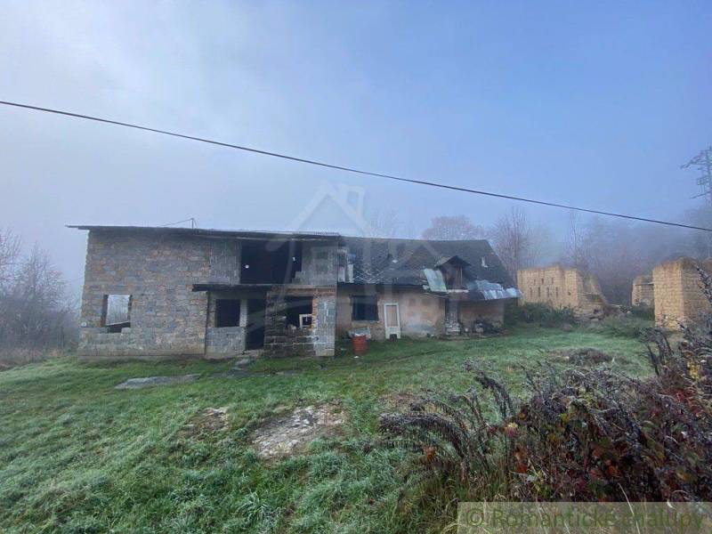 An old family house in the countryside surrounded by grass and a misty landscape.