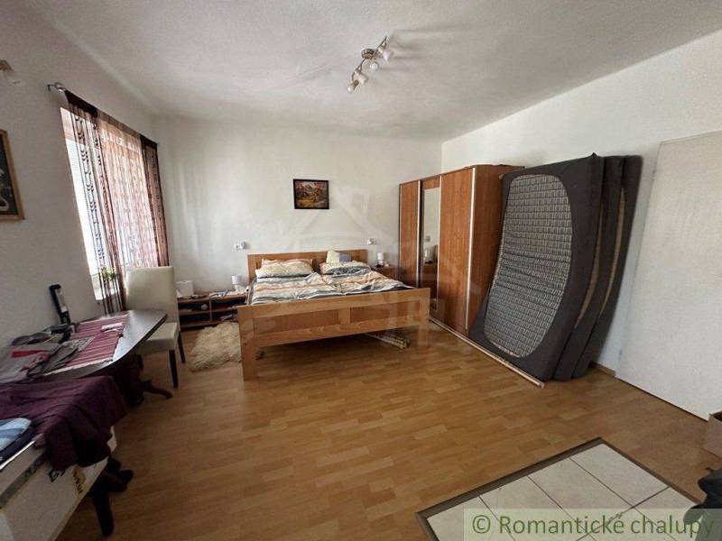 A bedroom with a parquet floor contains a double bed, wardrobes, and a desk. Family house.