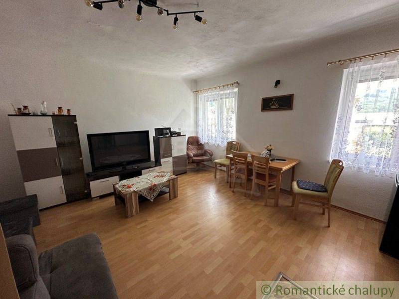 Living room in a family house with a television, sofa set, dining table, wooden floor.