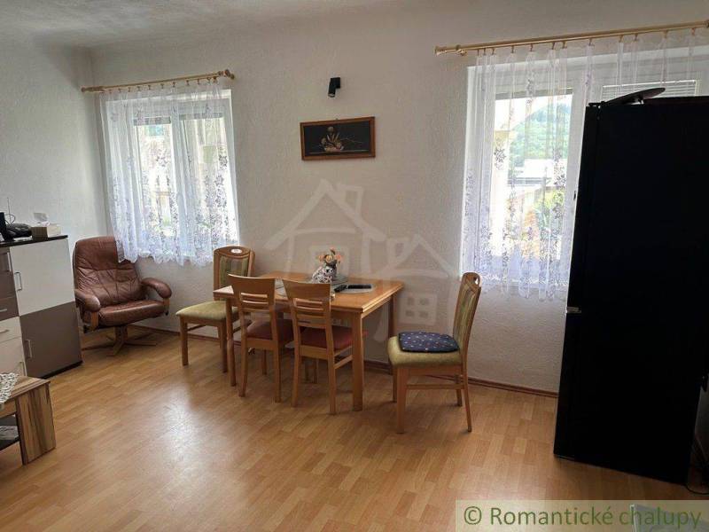 Dining room in a family house with furniture and windows with curtains, a comfortable chair, and flooring.