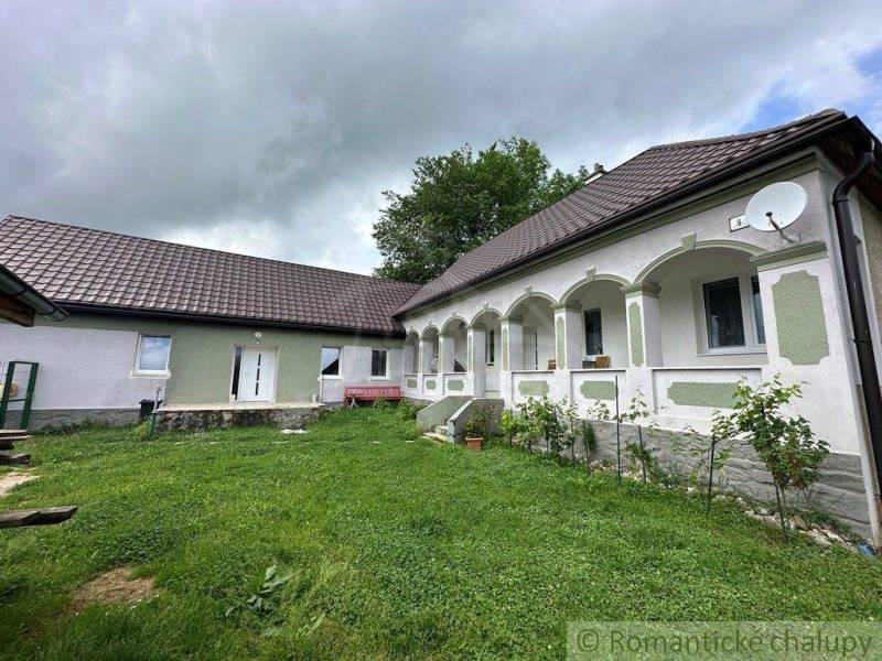 A family house with a white facade, arched arcade, and satellite, surrounded by a lawn.
