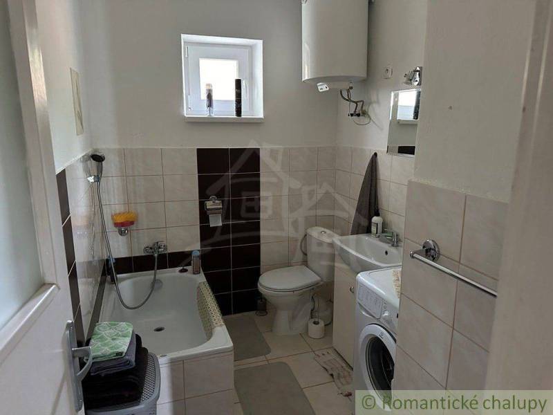 Compact bathroom in a family house with a bathtub, washing machine, and water heater.