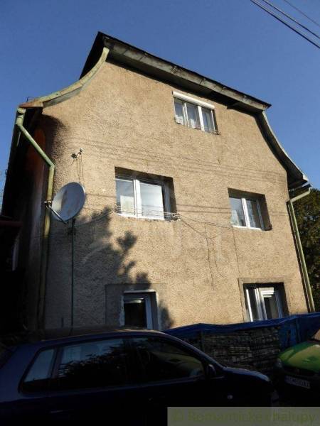 Stone family house with three floors, windows, and a satellite dish, surrounded by cars.