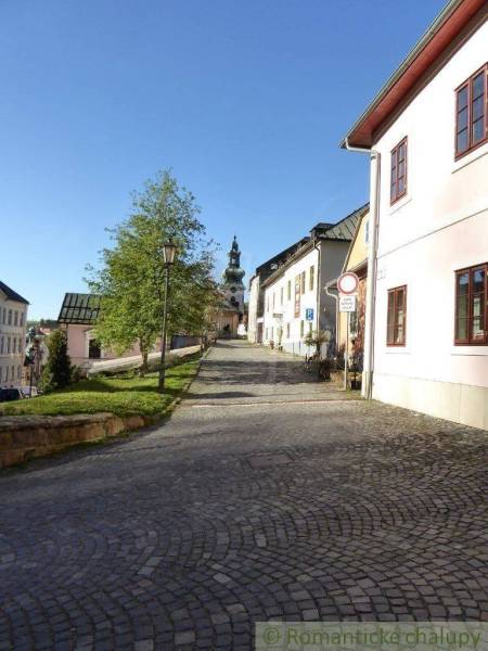 A narrow cobblestone alley with historic architecture and a church tower, ideal for a family home.