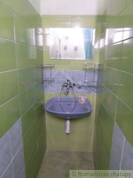 A narrow space with a sink and green tiles suitable for a family house.
