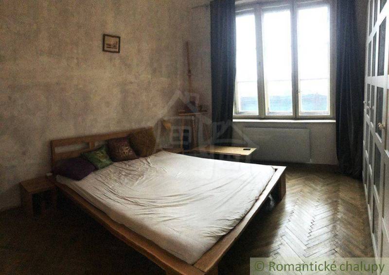 Bedroom in a two-room apartment, bed, window, curtains, minimalist wooden furniture.