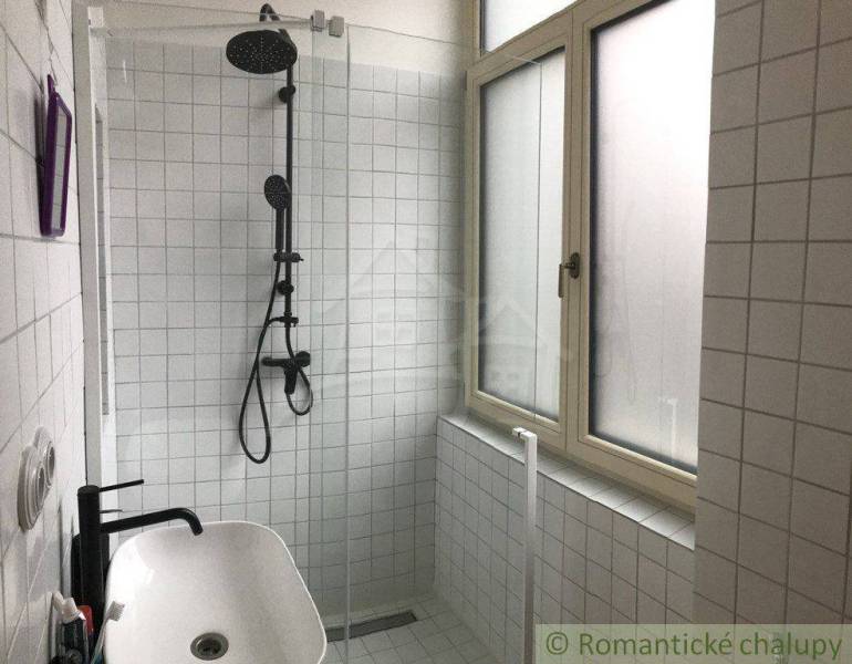 Bathroom with a shower, white tiles, and a sink in a 2-room apartment.
