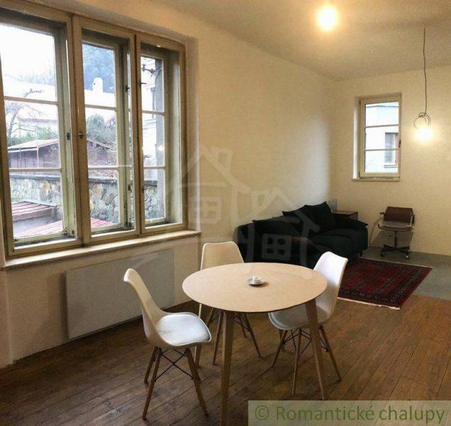 Dining nook with a window and a 2-room apartment; wooden floor, round table, chairs.