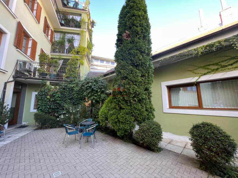 An outdoor space on Nitrianska Street with offices, chairs, and trees surrounded by greenery.