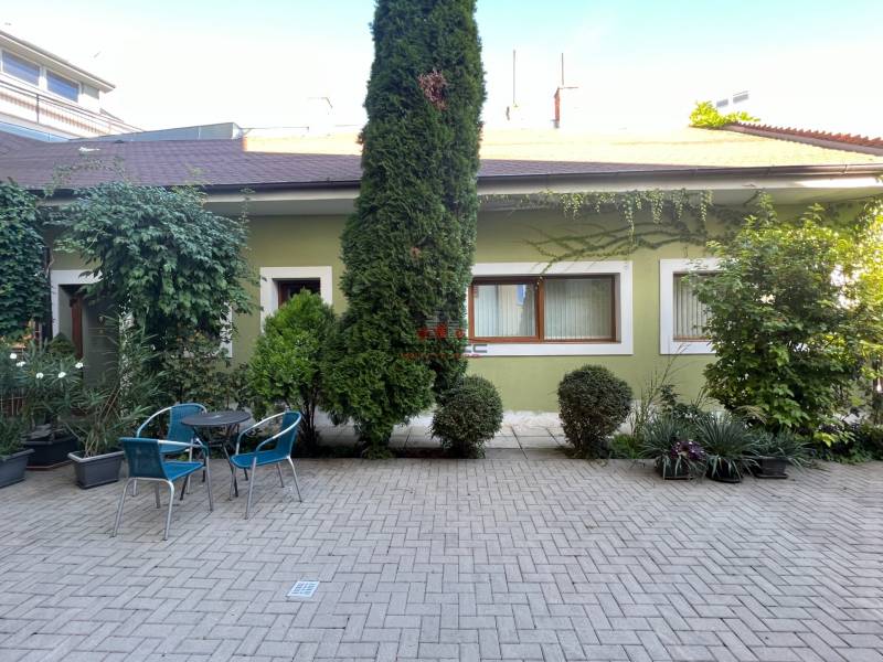A table with blue chairs on Nitrianska street, surrounded by greenery and offices.