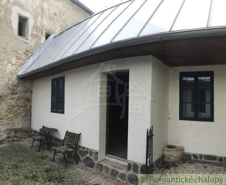 A picturesque cottage with charming stone paving and blue shutters in the shade of a peculiar property.