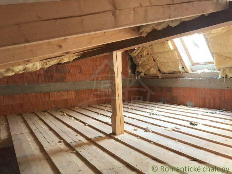 Attic with wooden beams, brick wall, and skylight, ideal for unique properties.