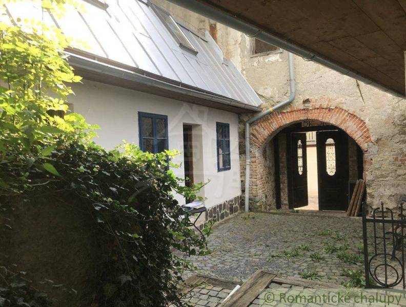 A cozy courtyard with historic architecture of unique properties, surrounded by plants and stones.