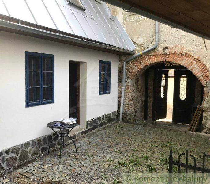A courtyard of a historic property with a stone arch and a table, ideal for relaxation.