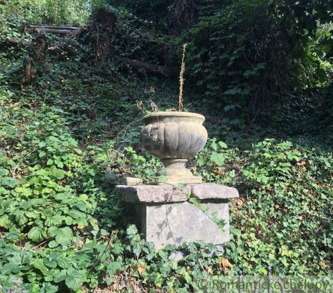 A stone vase overgrown with greenery, enhancing unique properties in a natural forest environment.