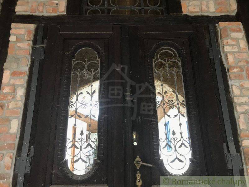Wooden door with decorative metal inlay, surrounded by a brick wall.
