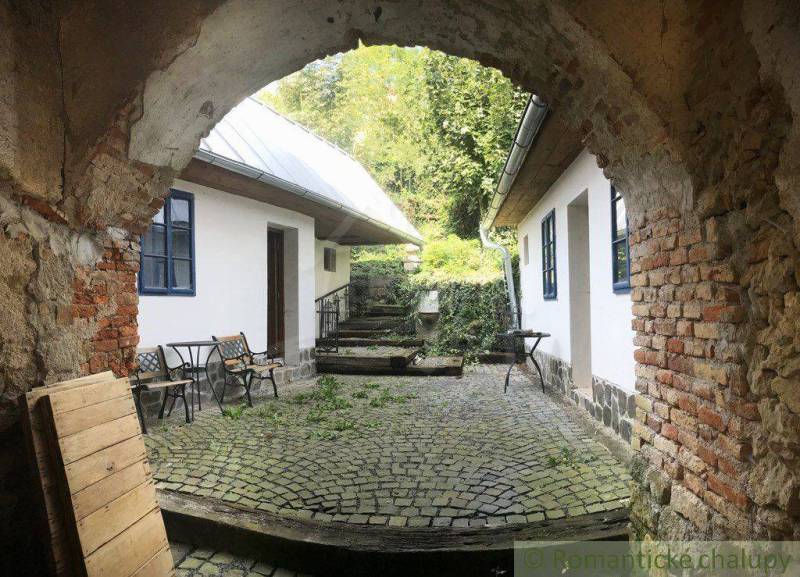 A stone courtyard with a rustic atmosphere complemented by wooden furniture and unique properties.