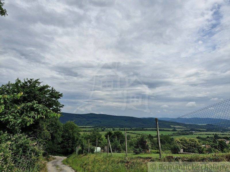 A rural environment with a road, hills, and clouds, suitable for a family house.