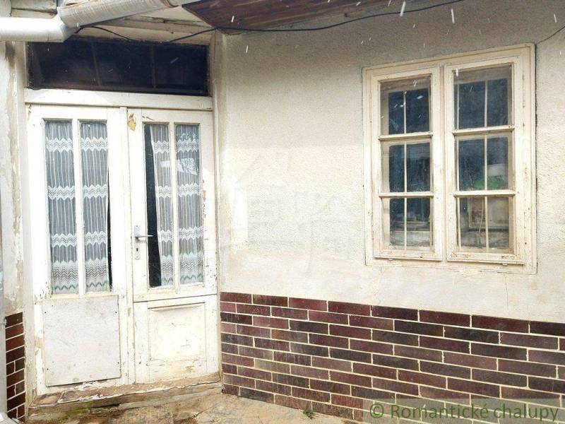 Old wooden door and window; traditional cottage with a brick plinth.