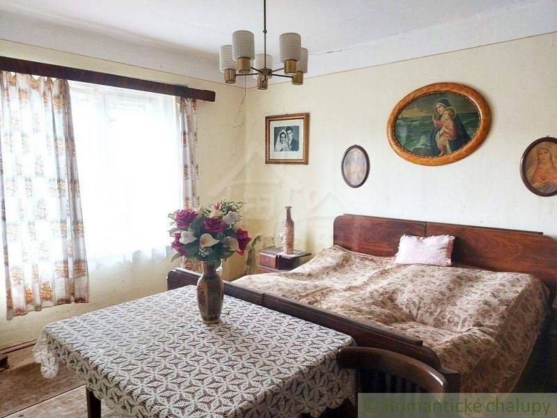 A room in a cottage with retro furniture, a rustic atmosphere, curtains, paintings, flowers.