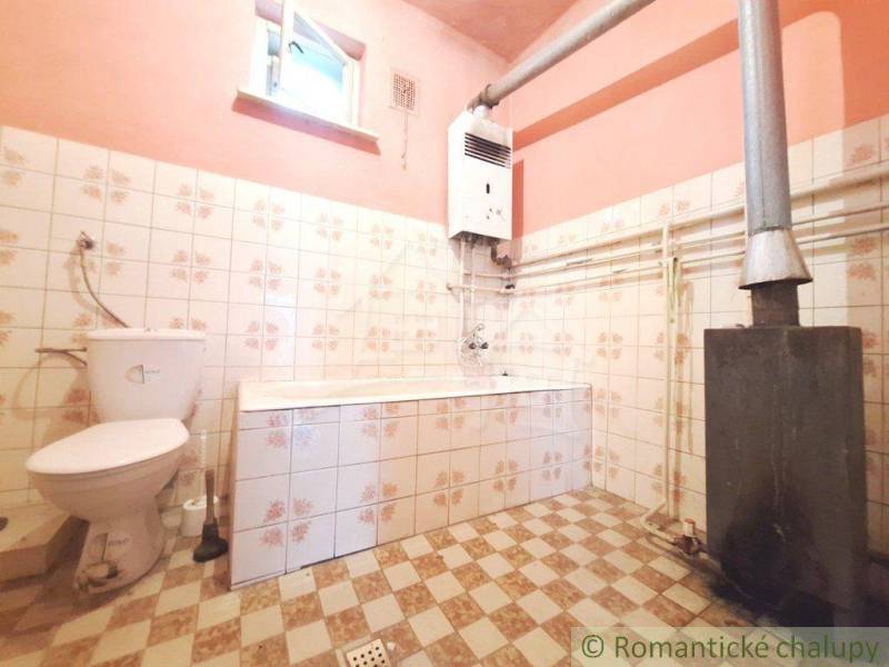 A bathroom with tiles and a stove, part of a family house with rustic charm.